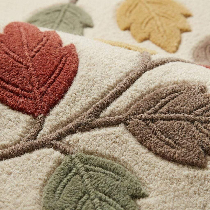 Translation missing: es.Close-up of textured botanical wool rug showing raised carved leaf design in terracotta, mustard, sage, and taupe on soft ivory background with plush pile detail