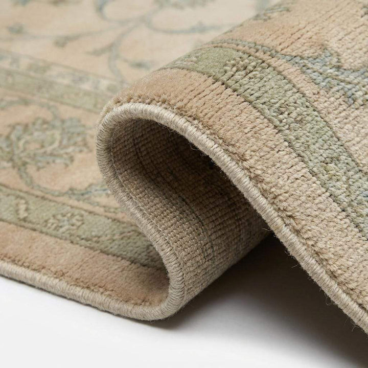 Translation missing: es.Close-up of rug showing fine wool pile texture, sage green vine detailing, and hand-crafted stitching