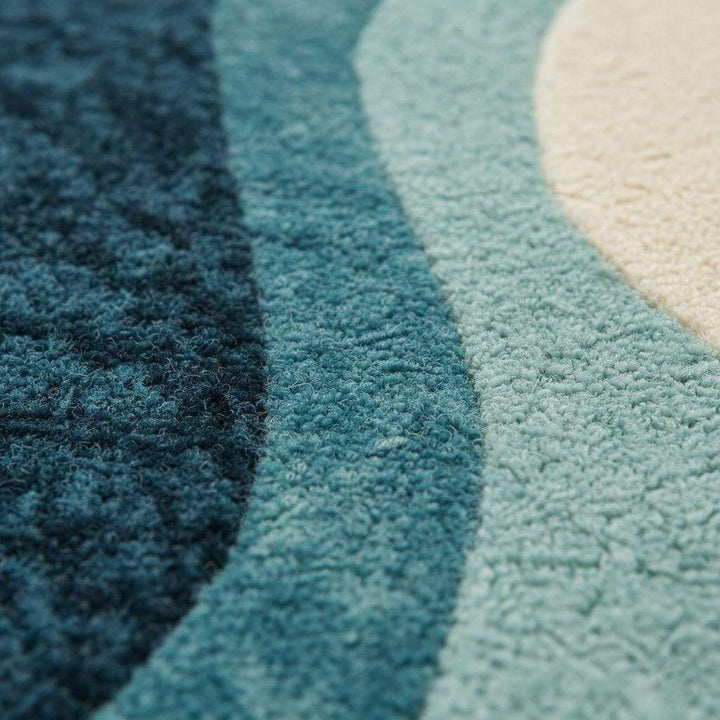 Translation missing: es.Blue wavy abstract area rug with coastal blues and teals in a modern living room setting