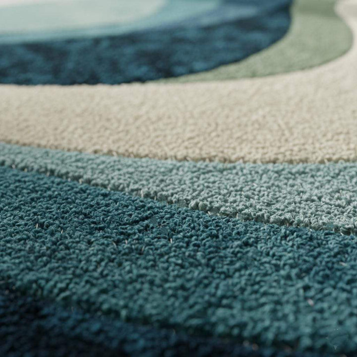Translation missing: es.Blue wavy abstract area rug with layered blues and teals in a modern coastal living room setup