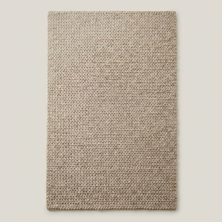 Translation missing: es.Chunky braided knit rug in neutral beige with thick textured yarn, ideal for cozy Nordic interiors and warm minimalist spaces