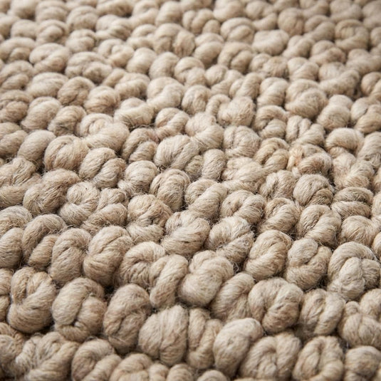Translation missing: es.Close-up of chunky knit rug texture showing thick looped yarn fibers, plush handmade construction and soft high pile beige wool detail