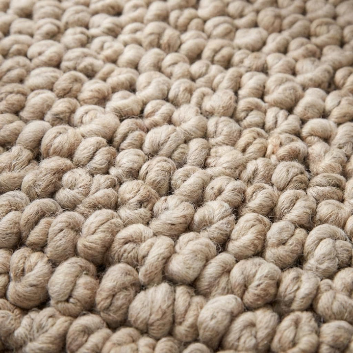 Translation missing: es.Close-up of chunky knit rug texture showing thick looped yarn fibers, plush handmade construction and soft high pile beige wool detail