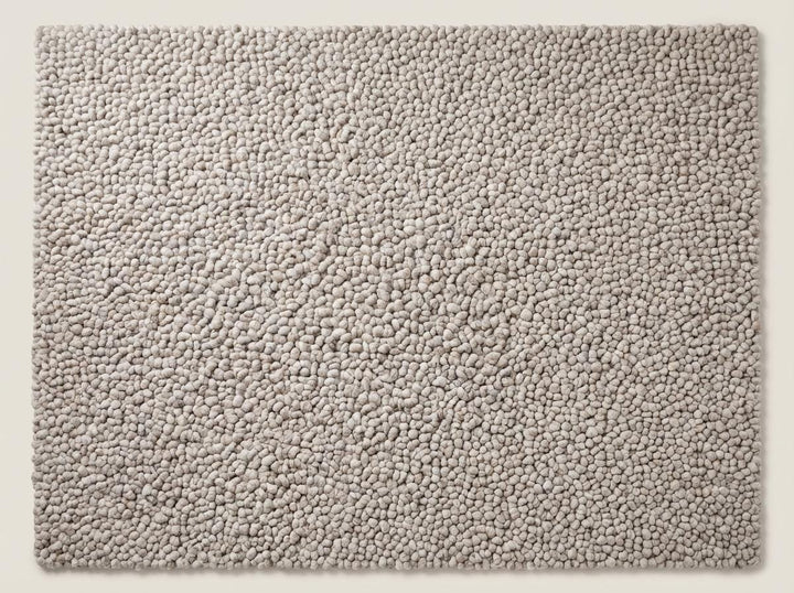 Translation missing: en.Top view of neutral chunky knit area rug with pebble texture, full surface visible showcasing consistent handmade loop design and soft beige tone