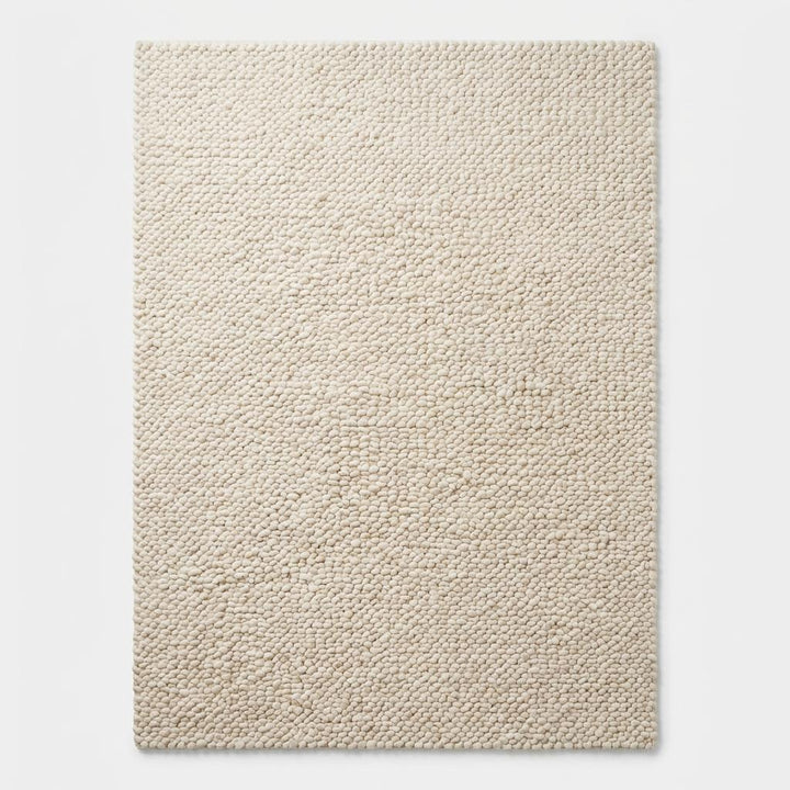 Translation missing: es.Top-down view of chunky knit wool area rug in neutral cream color displaying full textured surface, minimalist design, and organic modern style