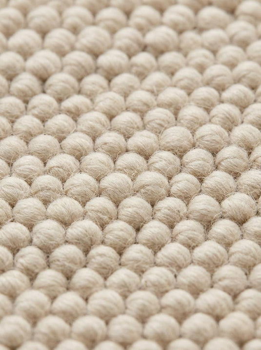 Translation missing: es.Detailed macro of dense loop weave and braided rug edge in neutral tone