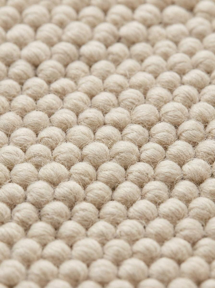 Translation missing: en.Detailed macro of dense loop weave and braided rug edge in neutral tone