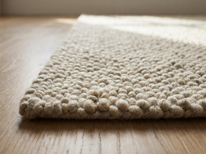 Translation missing: es.Edge detail of ivory looped rug highlighting thickness and structured finish
