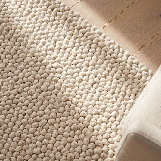 Translation missing: es.Chunky wool pom pom rug in neutral tones with soft textured wool balls for cozy boho nursery and living room decor