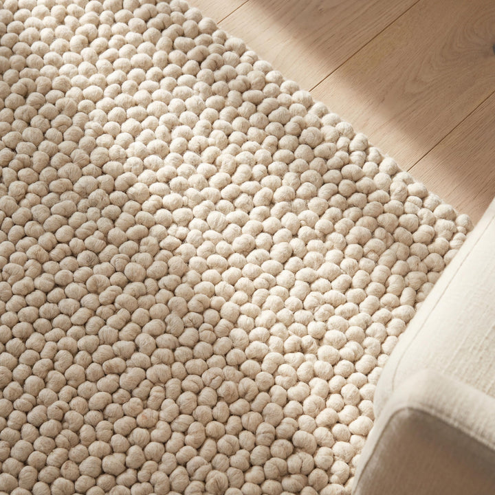 Translation missing: es.Chunky wool pom pom rug in neutral tones with soft textured wool balls for cozy boho nursery and living room decor