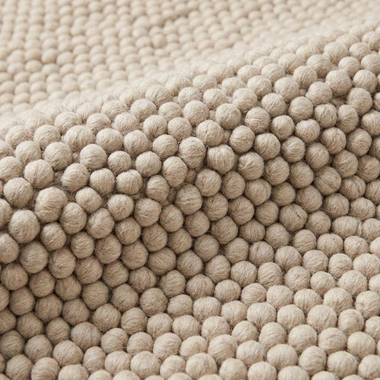 Translation missing: es.Close-up of chunky wool rug texture showing dense loop pile weave, soft natural fibers, and handcrafted thick wool knots in neutral cream tone