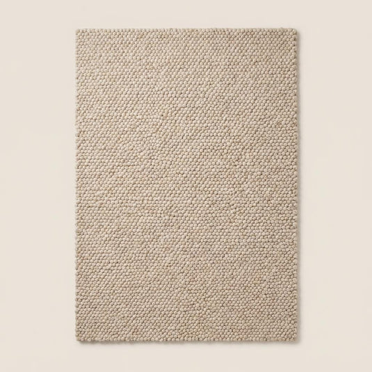 Translation missing: es.Top-down view of handmade cream chunky rug displaying uniform loop pile design, thick texture, and minimalist neutral style