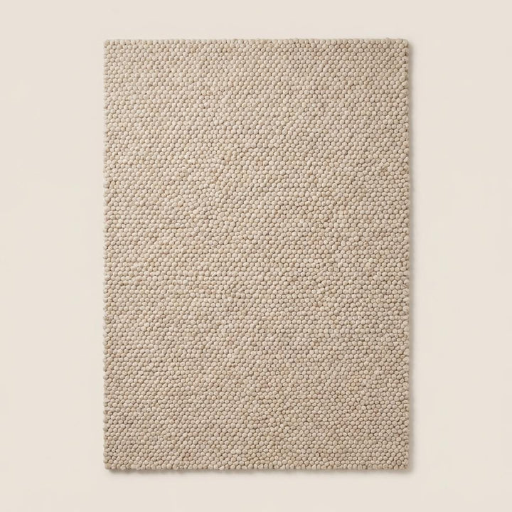 Translation missing: es.Top-down view of handmade cream chunky rug displaying uniform loop pile design, thick texture, and minimalist neutral style