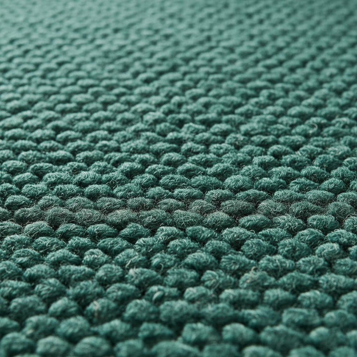 Translation missing: es.Close-up view of thick green wool rug with pebble-weave texture, cozy handcrafted carpet for living room or bedroom