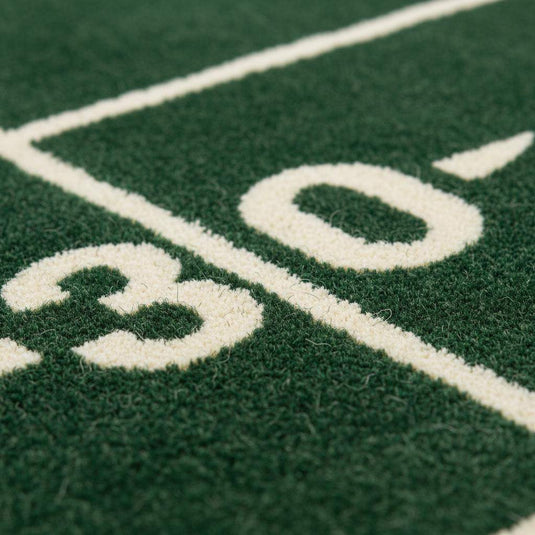 Translation missing: es.Close-up of plush green rug showing dense cut pile texture, clean white yard lines, and smooth fiber finish