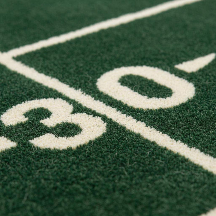 Translation missing: en.Close-up of plush green rug showing dense cut pile texture, clean white yard lines, and smooth fiber finish
