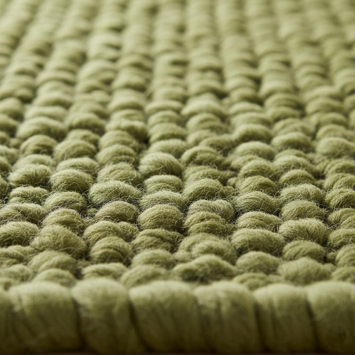 Translation missing: es.Close-up of textured green rug featuring dense pebble-like loops creating a moss-inspired, organic 3D surface