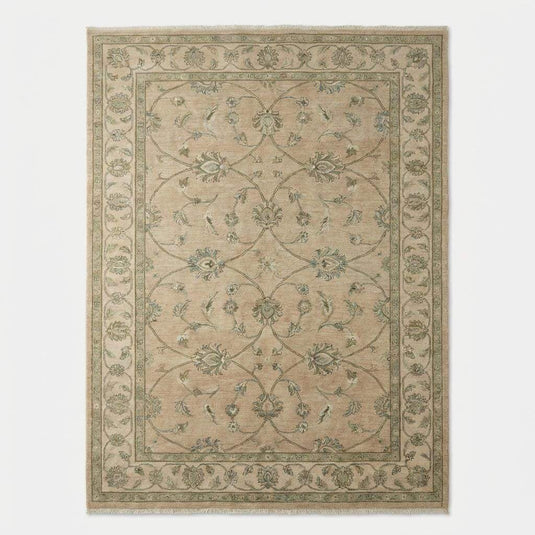 Translation missing: en.Overhead view of a traditional hand-knotted rug showing the symmetrical floral vine border and soft, muted earth-tone palette