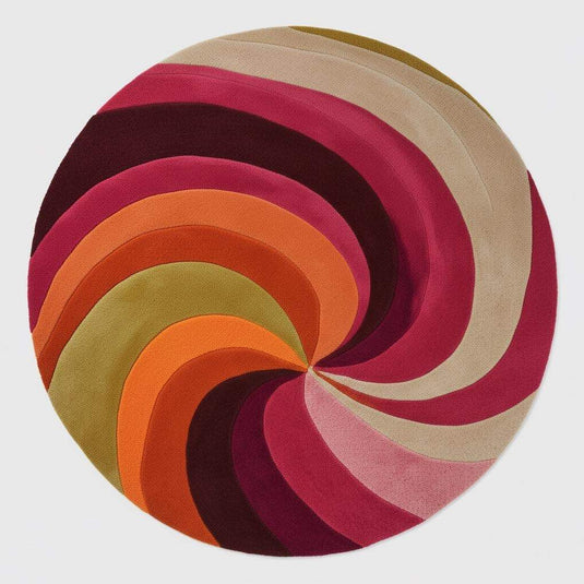 Translation missing: es.Circular 1970s inspired wool rug, bold pink and orange swirl, shown under a velvet sofa and hanging plants — mid-century modern decor idea