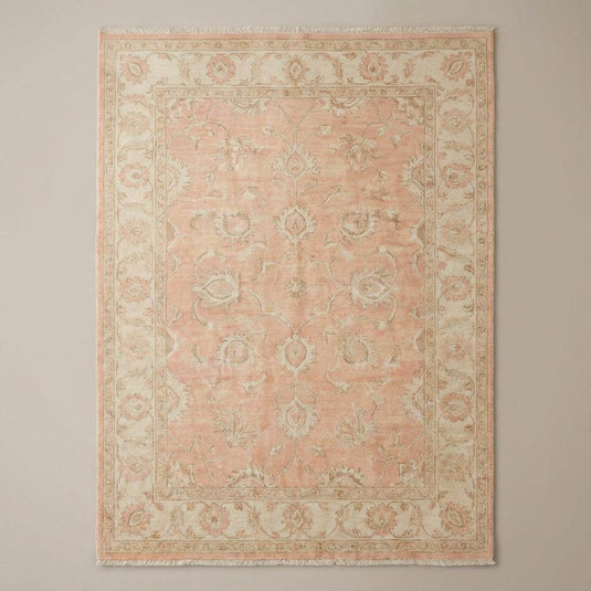 Translation missing: es.Traditional Persian-style floral vine area rug with muted sage and cream accents on warm wood flooring beside modern chair
