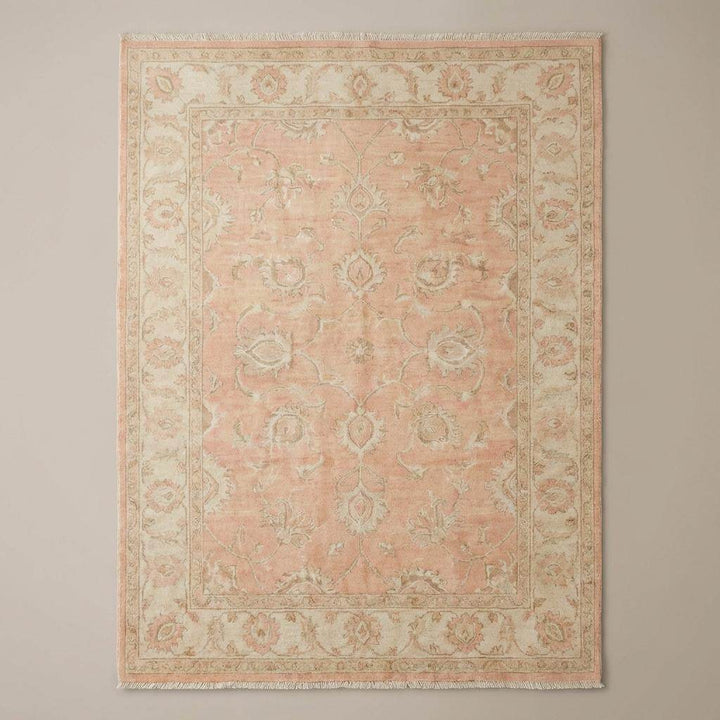 Translation missing: en.Traditional Persian-style floral vine area rug with muted sage and cream accents on warm wood flooring beside modern chair