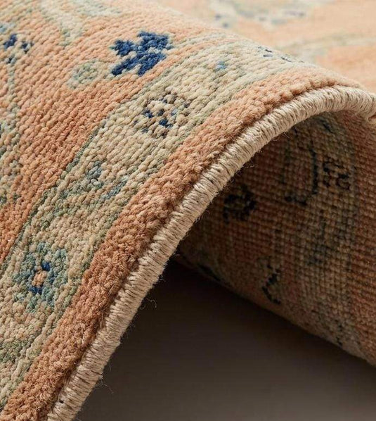 Translation missing: es.Close up detail showing hand-tied wool knots and soft pile texture of the apricot floral design