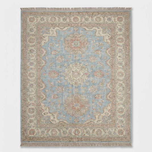 Translation missing: en.Angled view of pastel Turkish wool rug showing the intricate geometric border and integrated fringe tassels