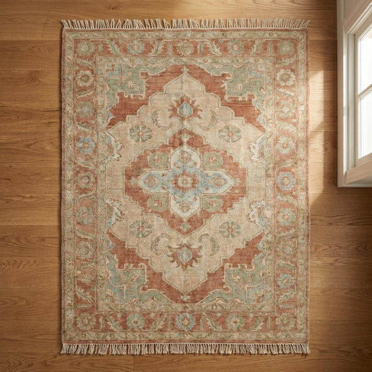 Translation missing: es.Angled perspective of muted Turkish style rug on wooden floor, showing fringe detail and soft color variations
