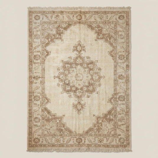 Translation missing: fr.Traditional neutral beige handmade wool area rug with floral border and central medallion placed on dark wooden floor