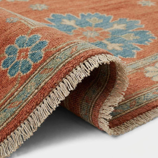 Translation missing: es.Close up of hand knotted wool pile texture showing individual knots and natural fiber variations in burnt orange and blue wool