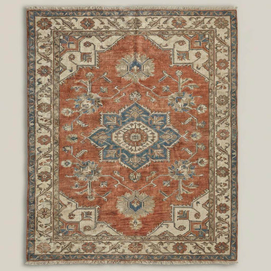 Translation missing: es.Large vintage-style wool rug in rust and cream tones, anchoring antique leather chairs and furniture in a cozy home