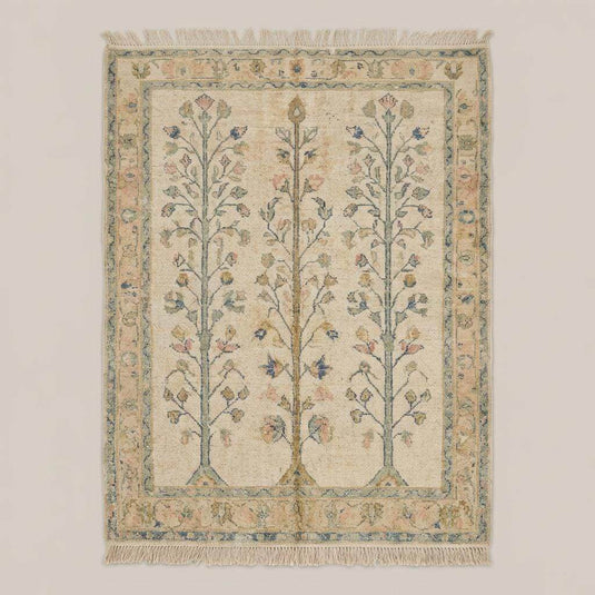 Translation missing: es.Beige and green botanical wool rug styled in a living room next to a rustic wooden chair on wood flooring
