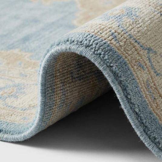 Translation missing: es.Close up of hand knotted wool rug showing dense individual knots, soft wool pile texture and intricate medallion detailing in blue and beige tones