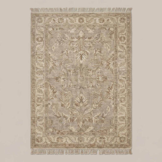Translation missing: es.Neutral vintage Persian inspired area rug with decorative border and fringe styled on wooden floor beside chair and pottery