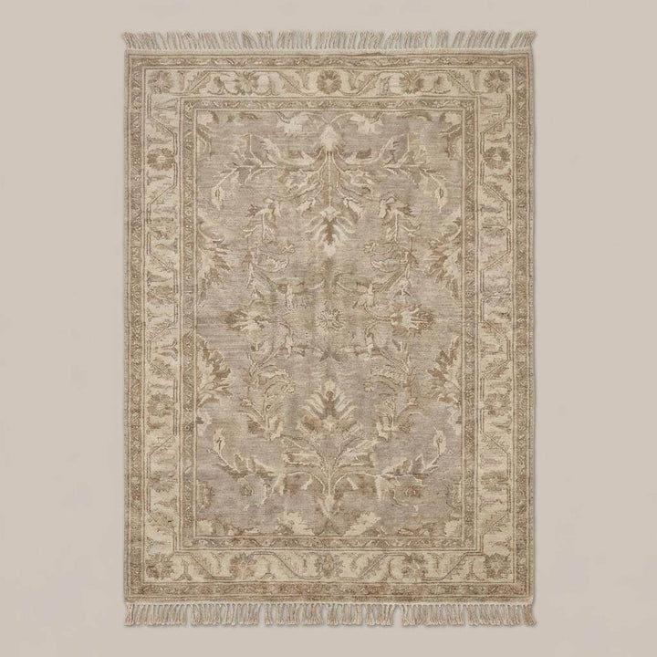 Translation missing: en.Neutral vintage Persian inspired area rug with decorative border and fringe styled on wooden floor beside chair and pottery