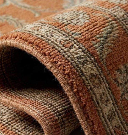 Translation missing: en.Close-up texture of a hand-knotted wool rug showing individual knot structure, low pile height, and intricate cream and olive green floral weaving