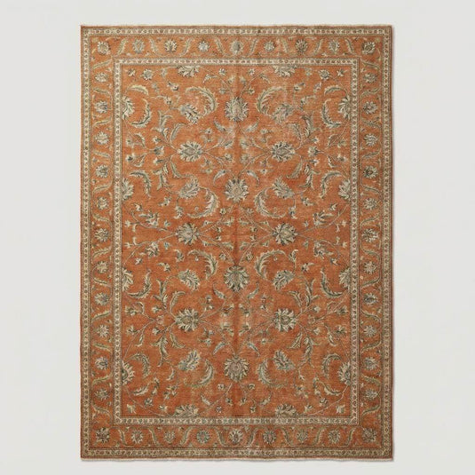 Translation missing: en.Overhead view of a large rust-colored area rug featuring a traditional floral border and a distressed, vintage-inspired transitional aesthetic