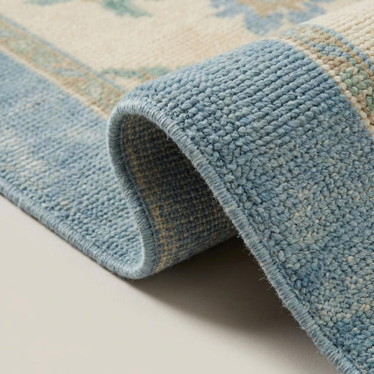 Translation missing: es.Close up of hand knotted wool rug showing individually tied knots, dense wool pile, and soft blue border fibers