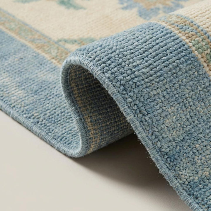 Translation missing: es.Close up of hand knotted wool rug showing individually tied knots, dense wool pile, and soft blue border fibers