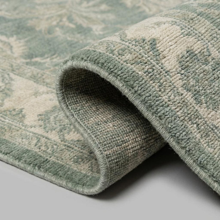 Translation missing: en.Close-up of hand knotted wool pile showing fine knot structure, natural fiber texture, and muted sage green vintage dye variation