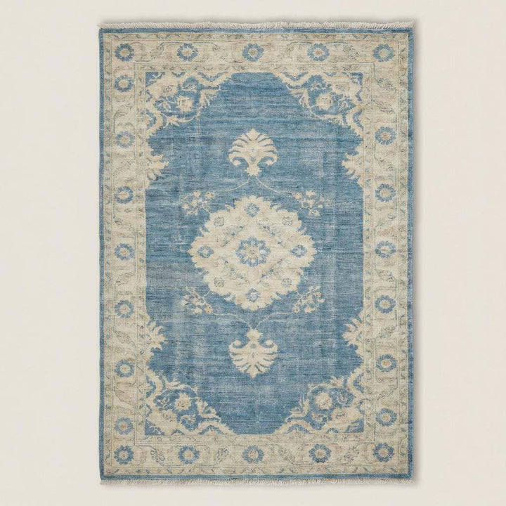 Translation missing: en.Rectangular blue medallion area rug with traditional Turkish Oushak pattern on light wood floor beside sofa