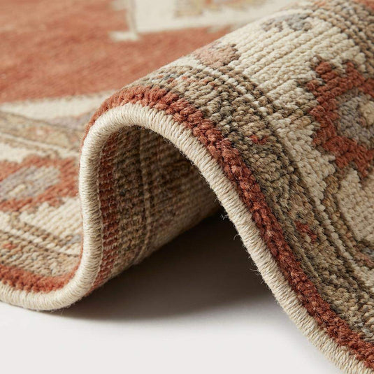 Translation missing: es.Close up of hand knotted wool pile texture showing individual knots, rich terracotta dye variation, and durable cotton fringe detail