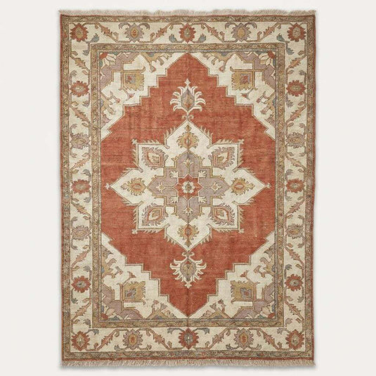 Translation missing: es.Angled view of rust and slate blue area rug styling a rustic farmhouse living room with a vintage wooden chair and natural light