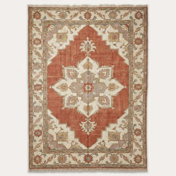 Translation missing: en.Angled view of rust and slate blue area rug styling a rustic farmhouse living room with a vintage wooden chair and natural light