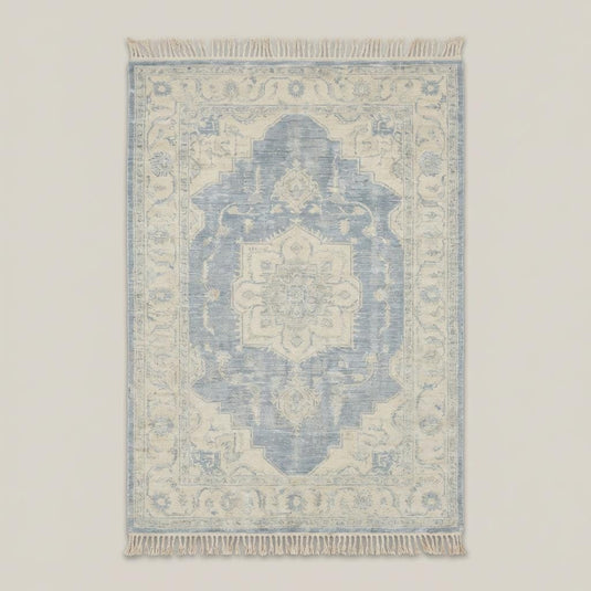 Translation missing: fr.Traditional blue and ivory medallion hand knotted rug styled beside curved sofa and wooden floor
