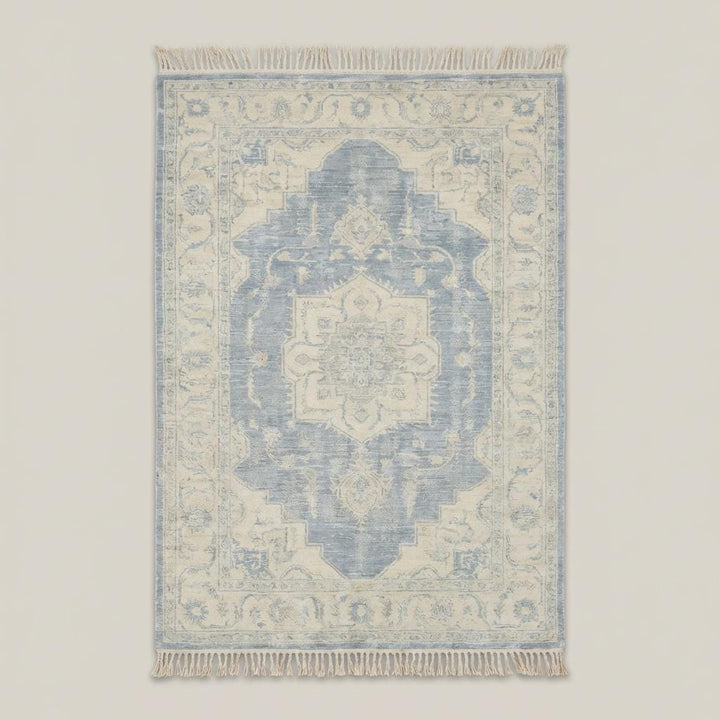 Translation missing: en.Traditional blue and ivory medallion hand knotted rug styled beside curved sofa and wooden floor