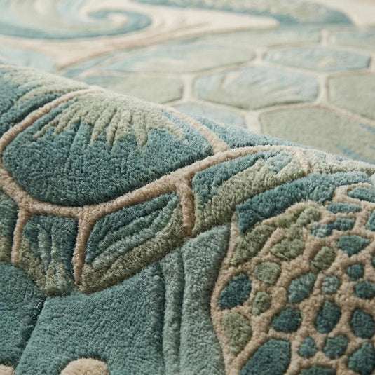 Translation missing: en.Close-up of hand tufted wool rug showing carved cut pile texture, sculpted sea turtle shell detailing, and raised wave patterns in teal and sand tones