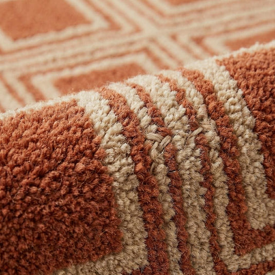 Translation missing: es.Close-up of hand tufted wool rug showing dense cut pile texture with carved high-low square pattern detailing in rust and cream tones