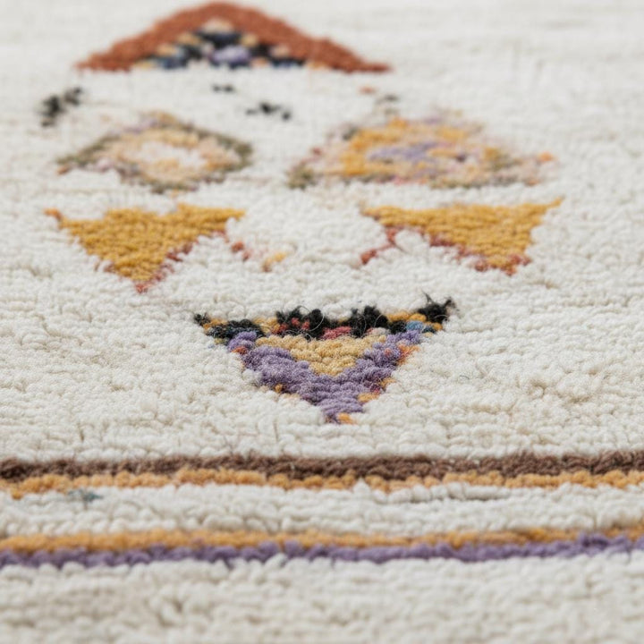 Translation missing: es.Close-up texture view of soft pastel boho wool rug showing blush, lilac and rust accent motifs