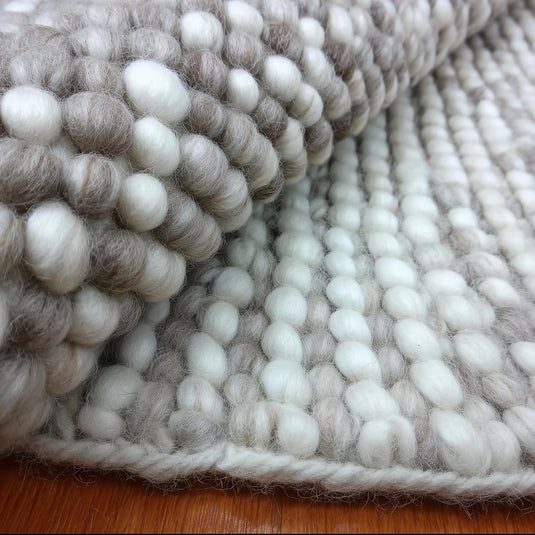 Translation missing: es.Handmade chunky wool rug with cream and beige pom pom design for cozy, natural home décor